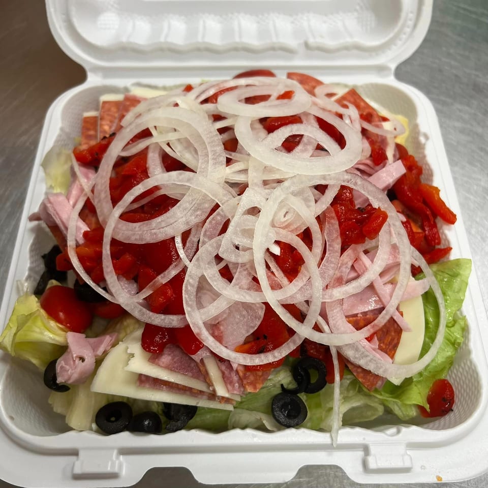 A large antipasto salad from American Pie of Rome, with lettuce, meats, cheeses, onions, and peppers.
